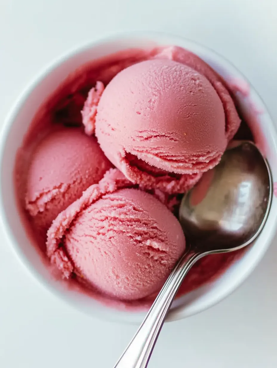 Eine Schüssel mit rosa Eis und einem Löffel darin.