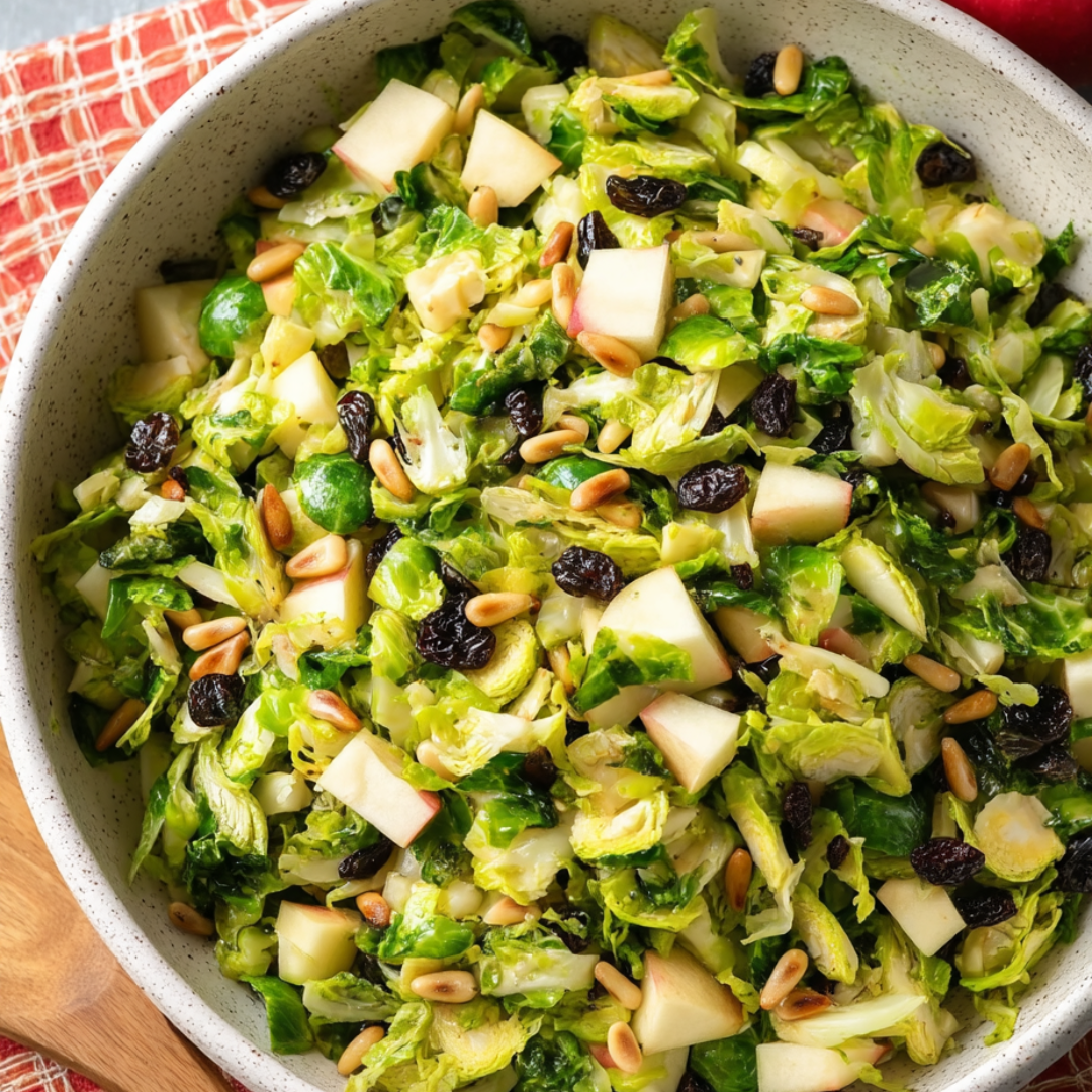 Eine Schale mit Salat, Apfelstücken, Nüssen und frischem Grün.