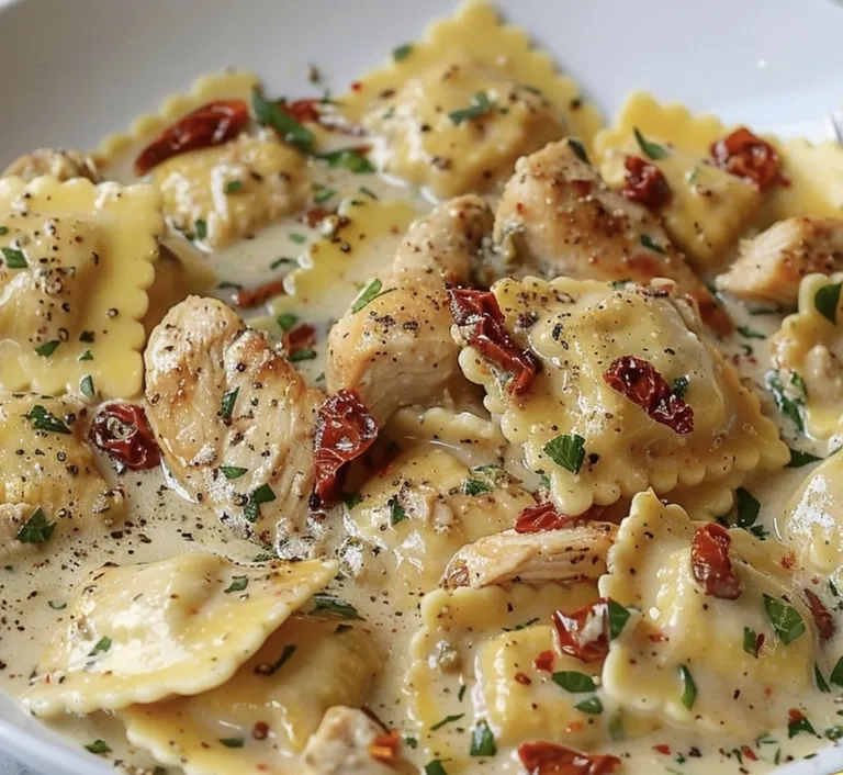 Eine Portion Pasta mit Huhn, Tomaten und roten Paprika auf einem Teller.