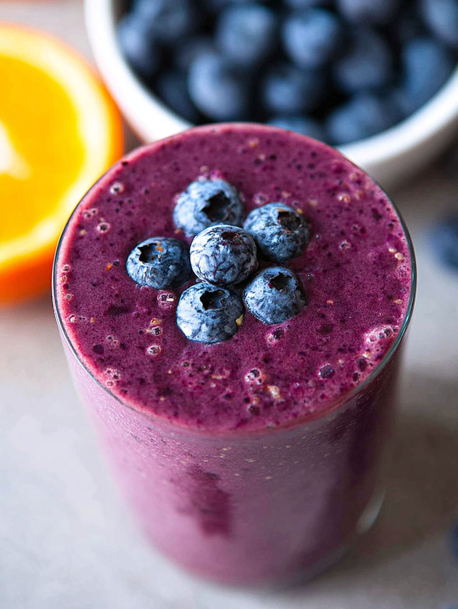 Ein Glas Blaubeer-Shake mit Blaubeeren oben drauf.