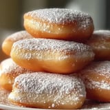 Ein Stapel mit Puderzucker bestäubter Donuts.