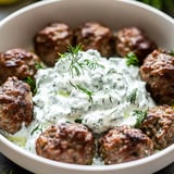 Eine Schale Fleischbällchen mit einem Klecks Sauerrahm obendrauf.