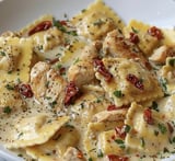 Eine Portion Pasta mit Huhn, Tomaten und roten Paprika auf einem Teller.