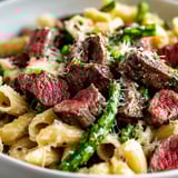 Bunter Pastateller mit Steak und Spargel.