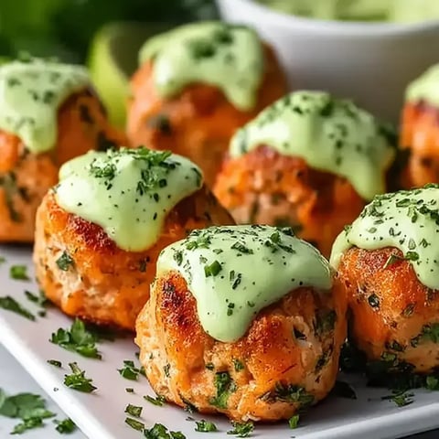 Ein Teller mit Lachsbällchen und Sauce.