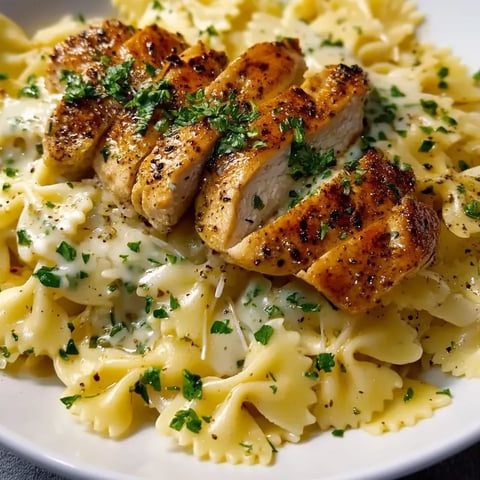 Teller mit Pasta, belegt mit Hühnchen und frischen Kräutern.