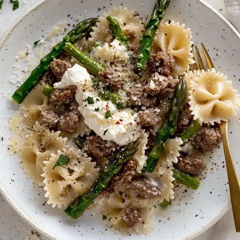 Ein Teller Nudeln mit Fleisch und Käse obendrauf.
