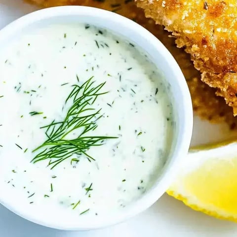 Eine Schüssel Sauce mit grünen Kräutern darin.