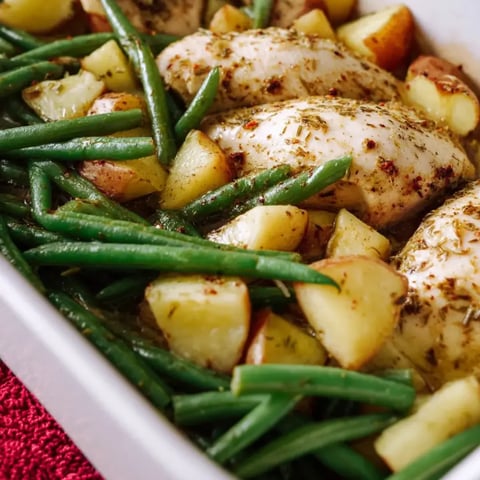 Eine weiße Schüssel gefüllt mit Huhn, Kartoffeln und Grünbohnen.