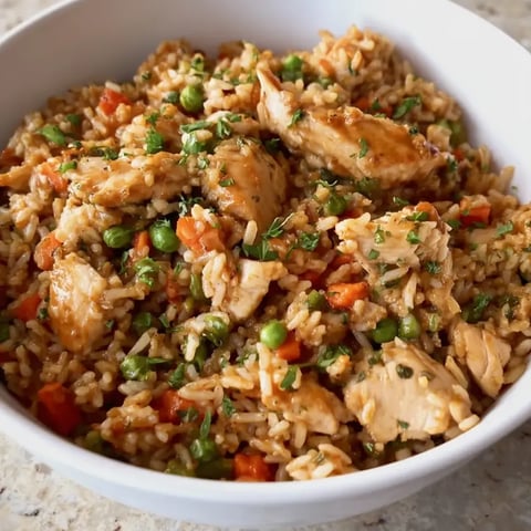 Eine Schüssel Reis mit Hähnchen und Erbsen.