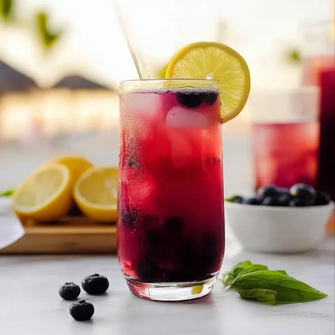 Ein Glas roter Saft mit Zitrone und Blaubeeren.