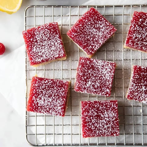 Ein Blech mit roten Gelee-Streifen und Puderzucker obendrauf.
