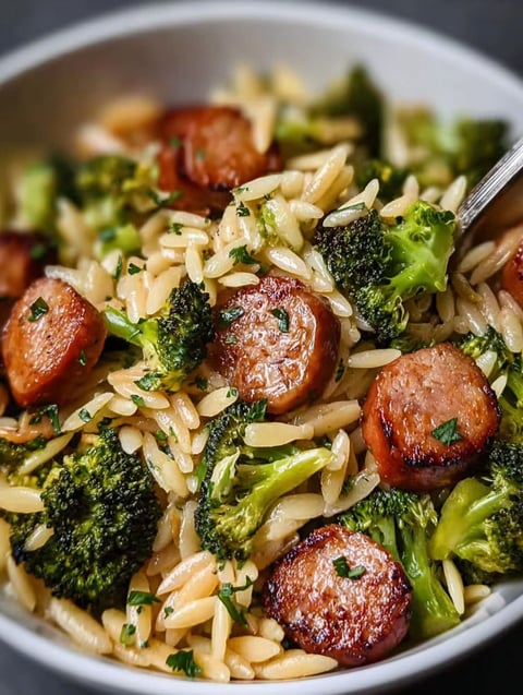 Eine Schüssel mit Reis, Wurst und Brokkoli.