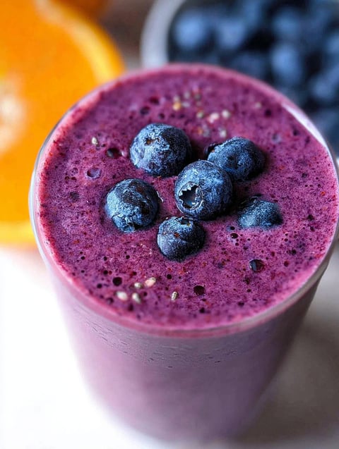 Ein Glas Blaubeer Smoothie mit einer Blaubeere drin.