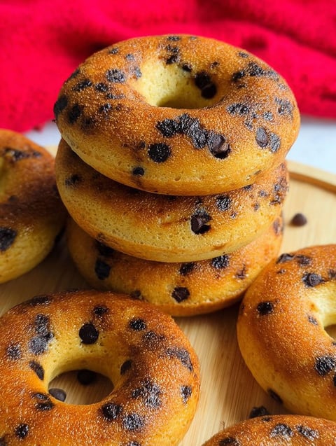 Schoko Chip Donuts auf einem Holzbrett gestapelt.